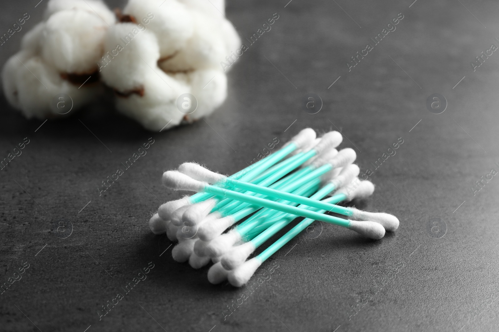 Photo of Pile of cotton swabs and flowers on grey table