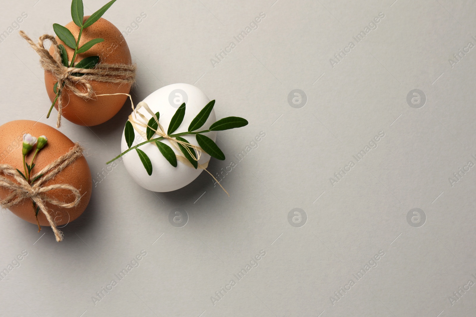 Photo of Festively decorated chicken eggs on light grey background, flat lay with space for text. Happy Easter