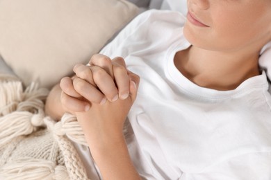 Photo of Boy with clasped hands praying in bed, closeup