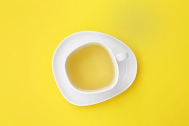 Photo of Cup of tea and saucer on yellow background, top view