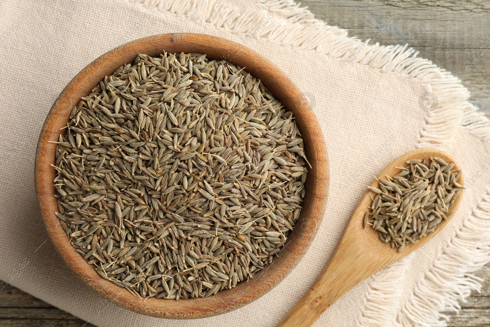 Photo of Bowl of caraway seeds and spoon on table, top view
