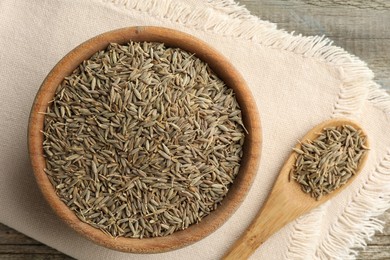 Bowl of caraway seeds and spoon on table, top view