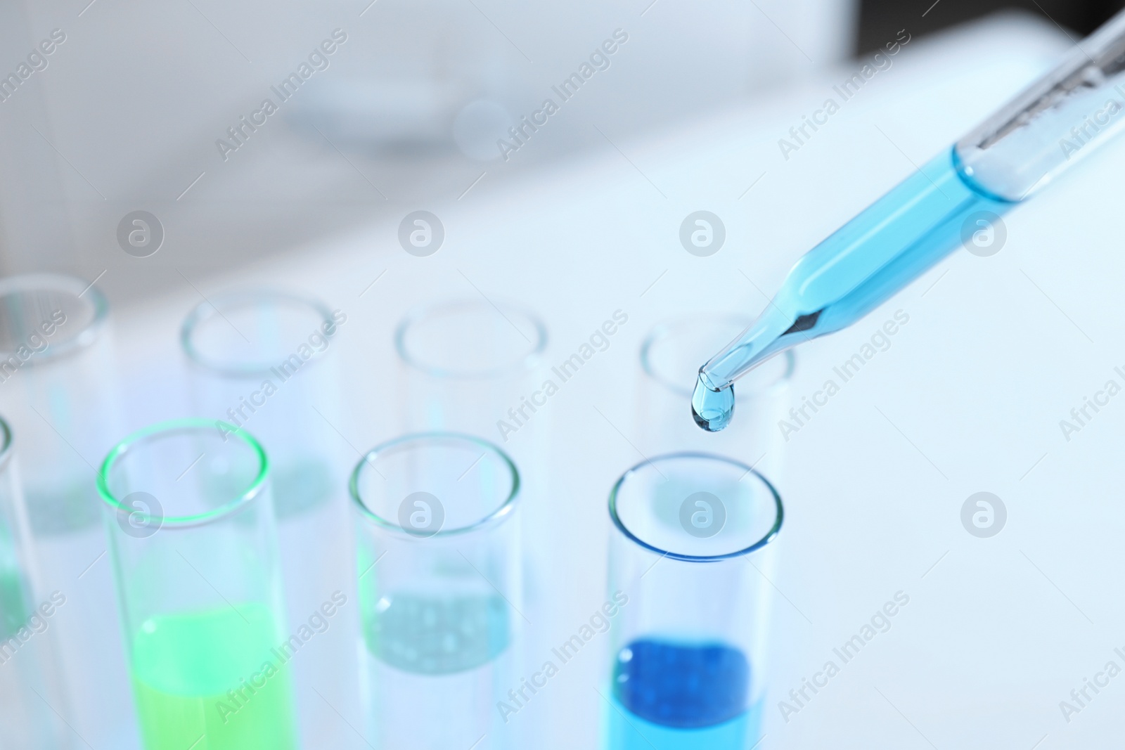 Photo of Dripping sample into test tube in chemistry laboratory, closeup