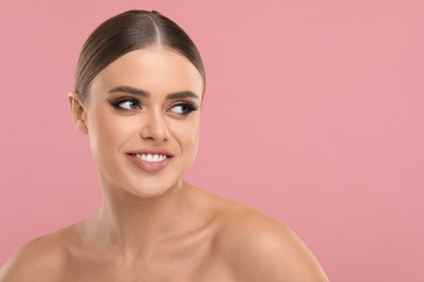 Photo of Happy woman with makeup on pink background, space for text