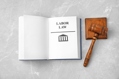 Photo of Open book with words LABOR LAW and gavel on light background, top view