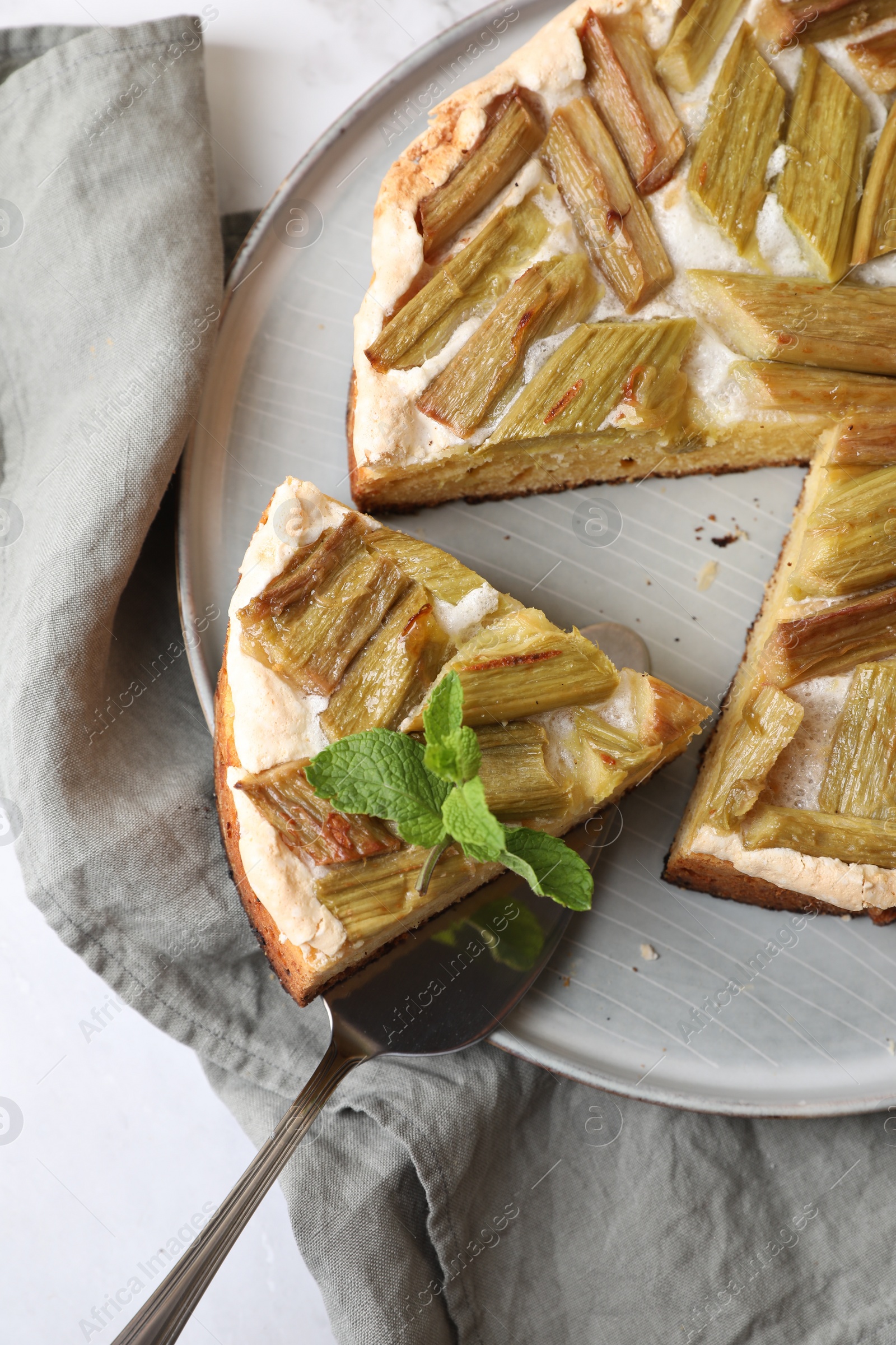 Photo of Freshly baked rhubarb pie and spatula on white table, above view