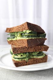 Photo of Tasty sandwiches with cucumber, cream cheese and dill on grey table, closeup