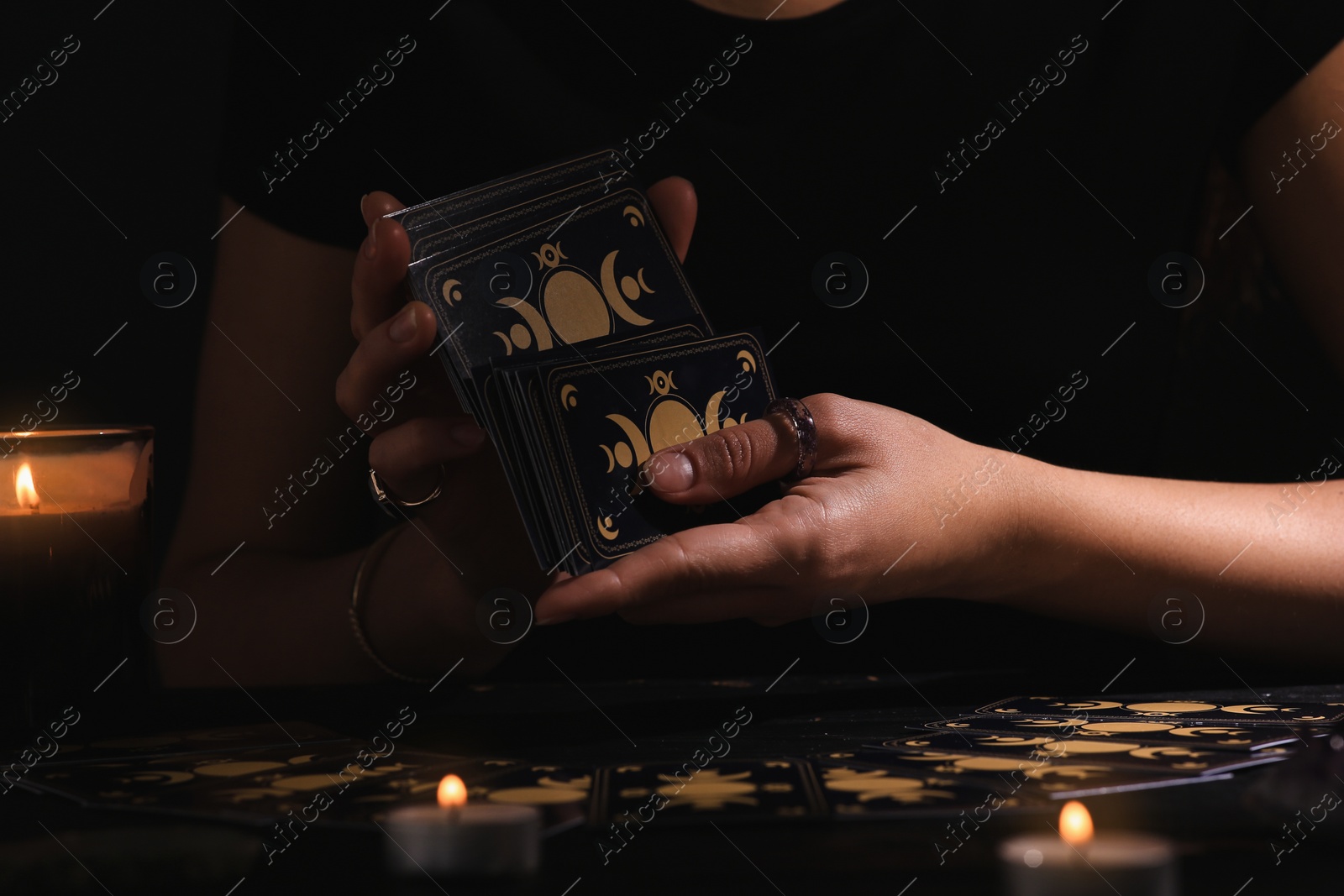 Photo of Soothsayer shuffling tarot cards at table in darkness. Fortune telling