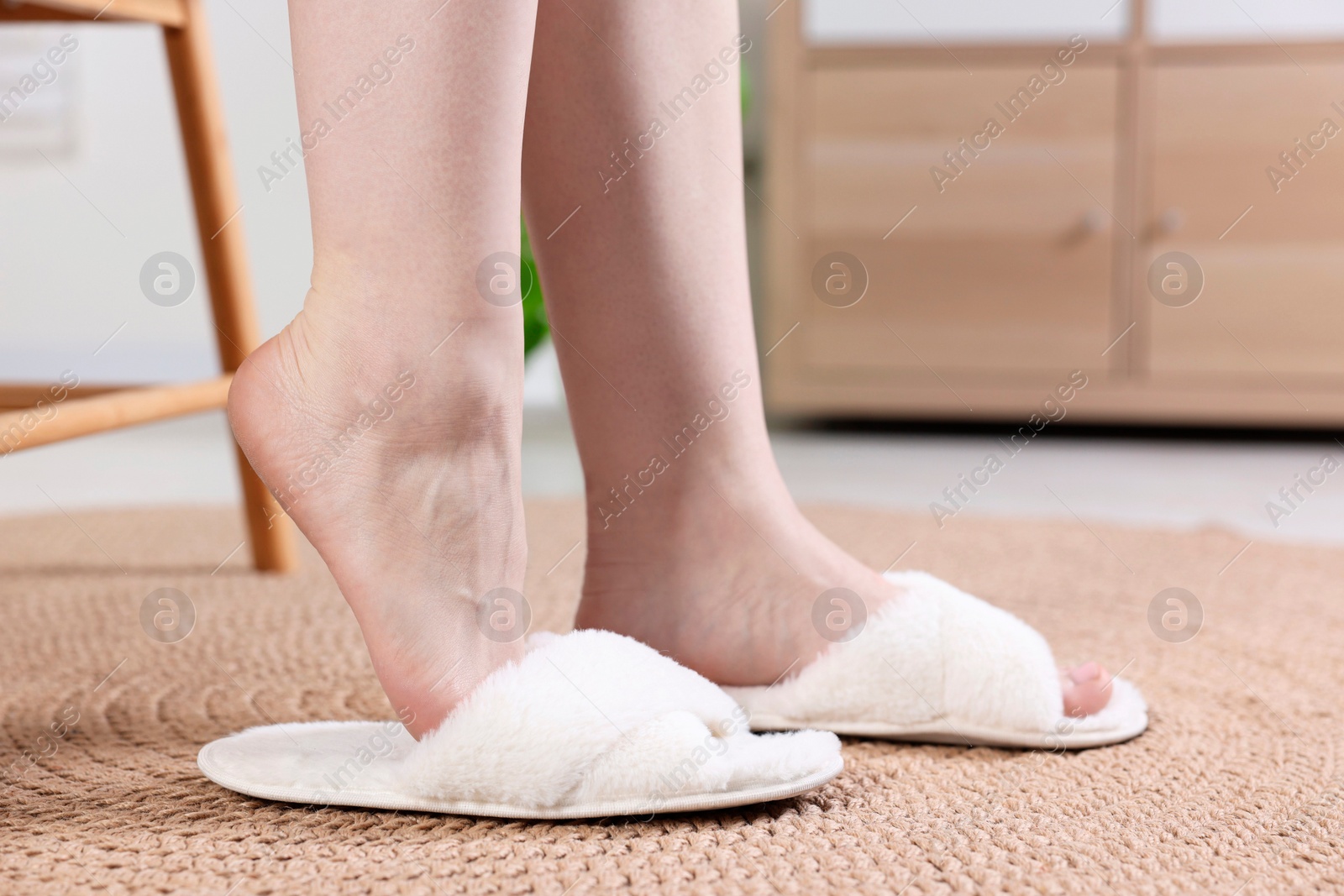 Photo of Woman wearing white soft slippers at home, closeup