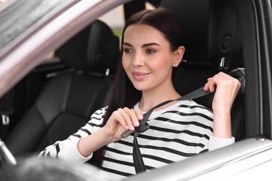 Photo of Woman fastening safety seat belt inside modern car