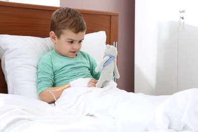 Little child with intravenous drip and toy in hospital bed