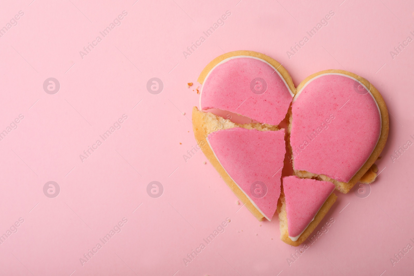 Photo of Broken heart shaped cookie on pink background, top view with space for text. Relationship problems concept