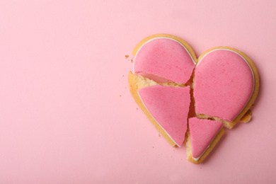 Photo of Broken heart shaped cookie on pink background, top view with space for text. Relationship problems concept