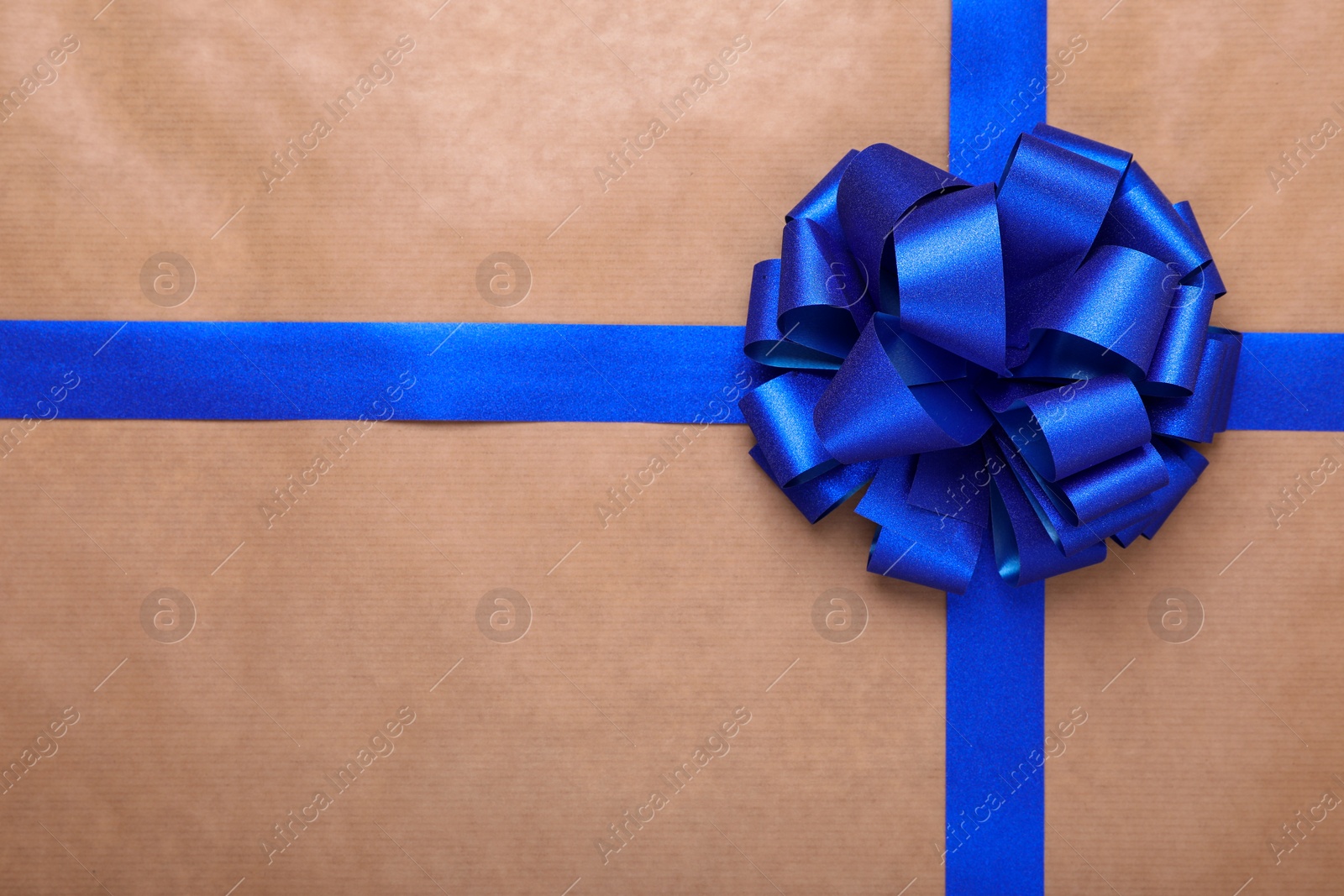 Photo of Blue ribbon with bow on beige background, top view