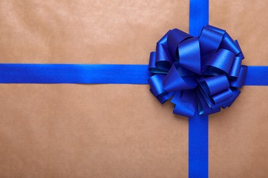 Photo of Blue ribbon with bow on beige background, top view