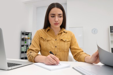 Photo of Unhappy young female intern at table in office