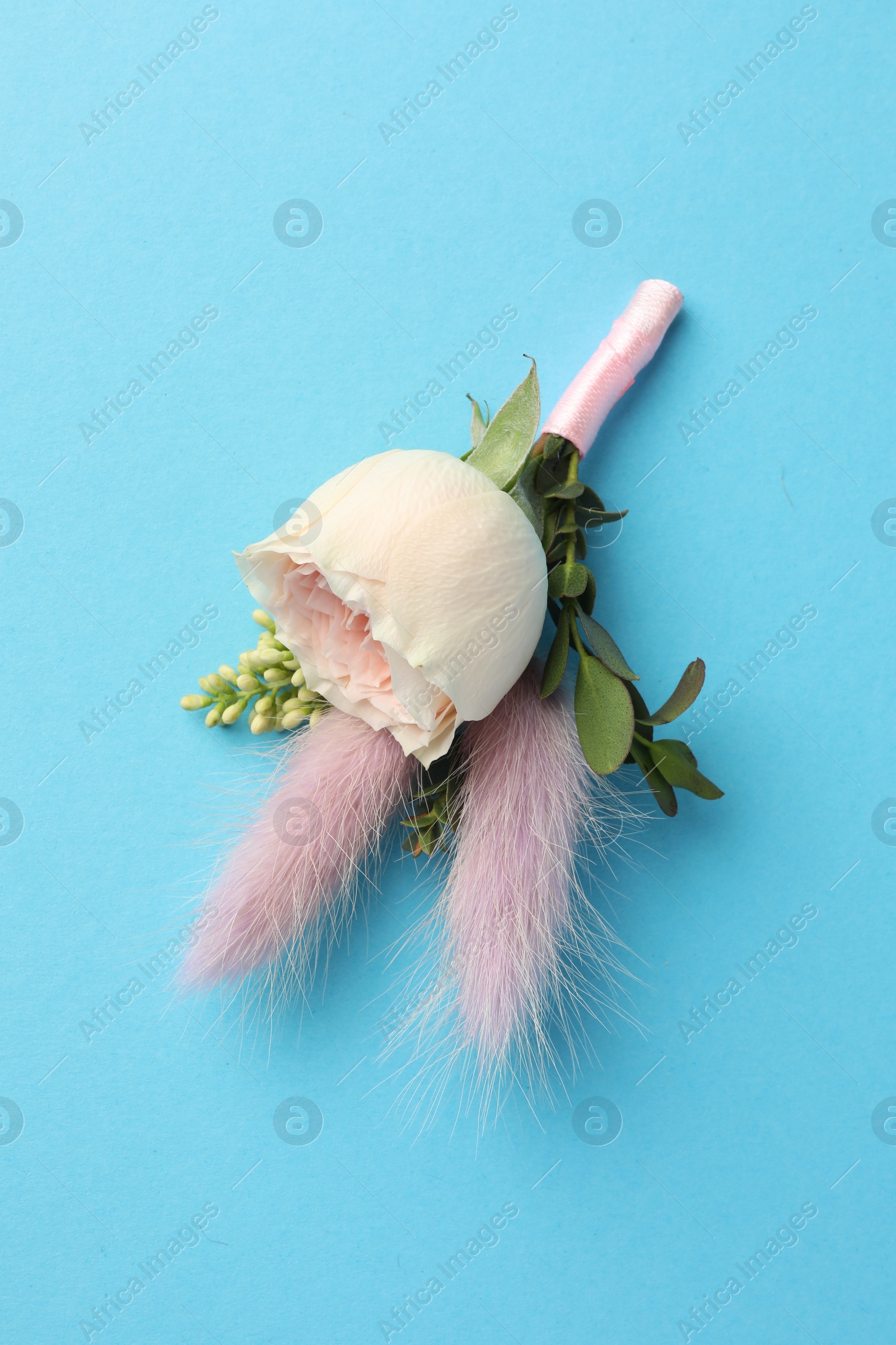 Photo of Small stylish boutonniere on light blue background, top view