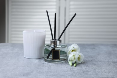 Reed diffuser, scented candle and eustoma flowers on gray marble table