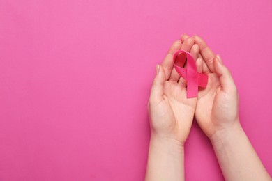 Photo of Breast cancer awareness. Woman with pink ribbon on color background, top view. Space for text