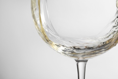 Pouring white wine into glass on light background, closeup