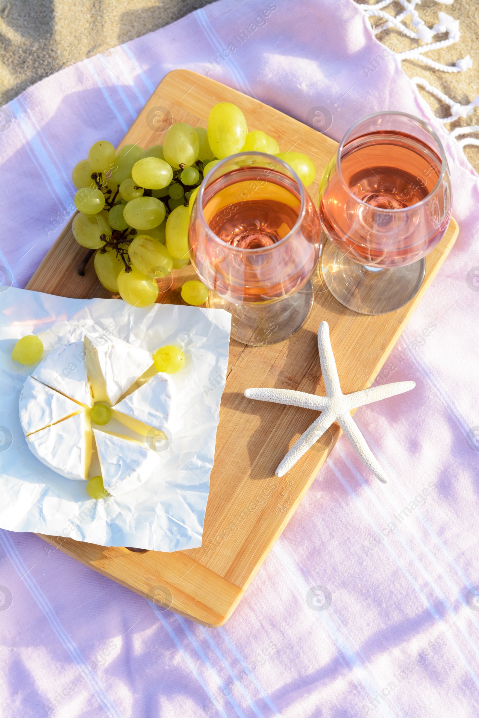 Photo of Glasses with rose wine and snacks on picnic blanket, above view