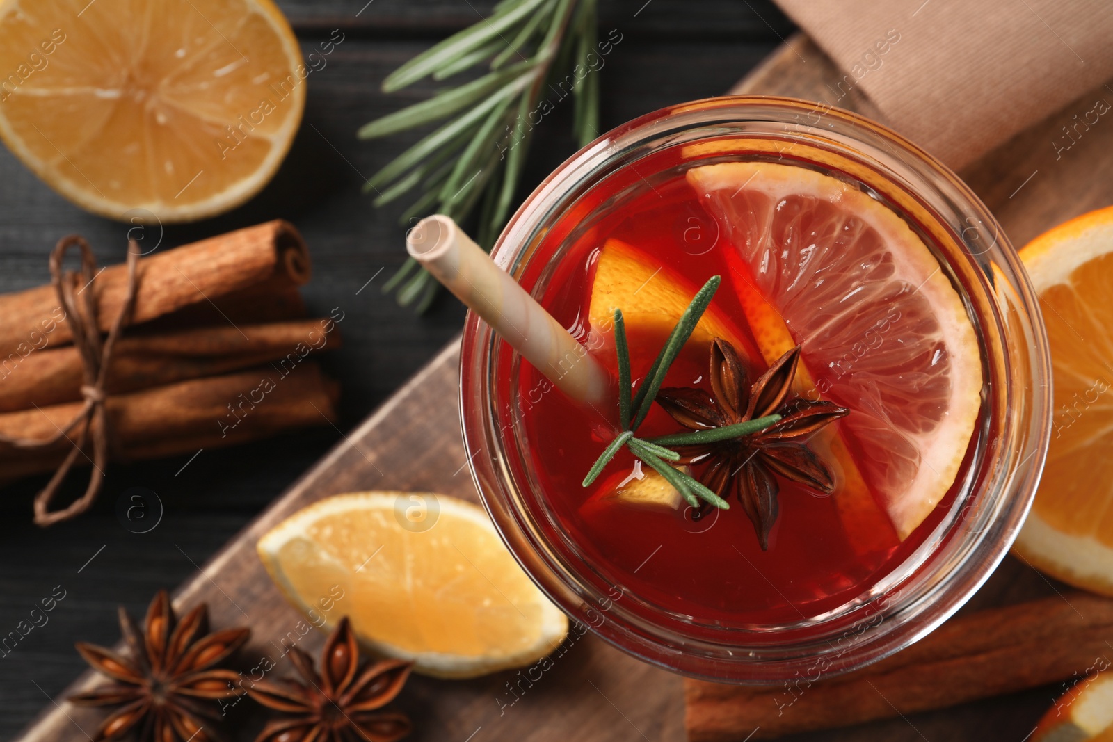 Photo of Aromatic punch drink and ingredients on black wooden table, flat lay