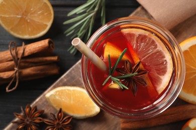 Photo of Aromatic punch drink and ingredients on black wooden table, flat lay