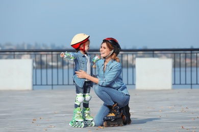 Mother and her daughter wearing roller skates on city street