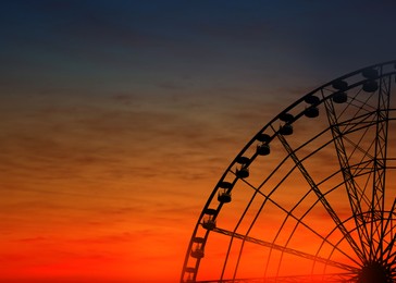 Image of Beautiful large Ferris wheel outdoors at sunset, space for text