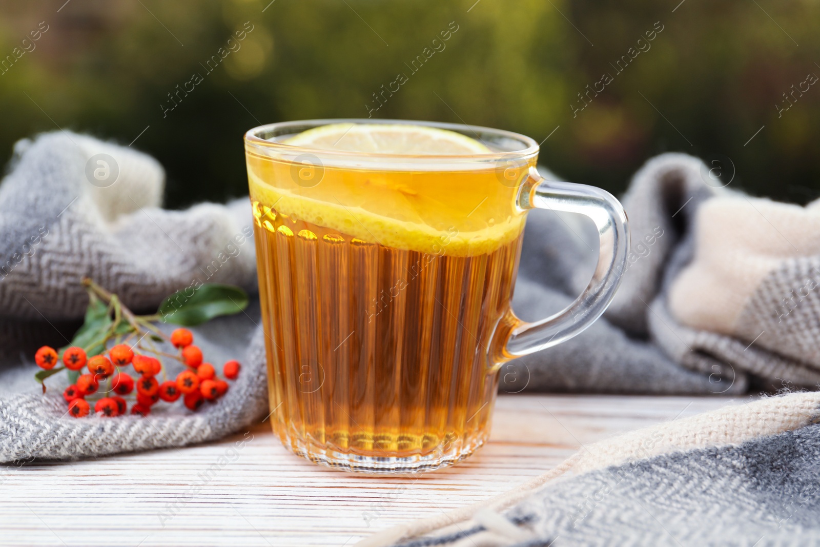 Photo of Cup of hot drink and scarf on window sill indoors. Cozy autumn atmosphere