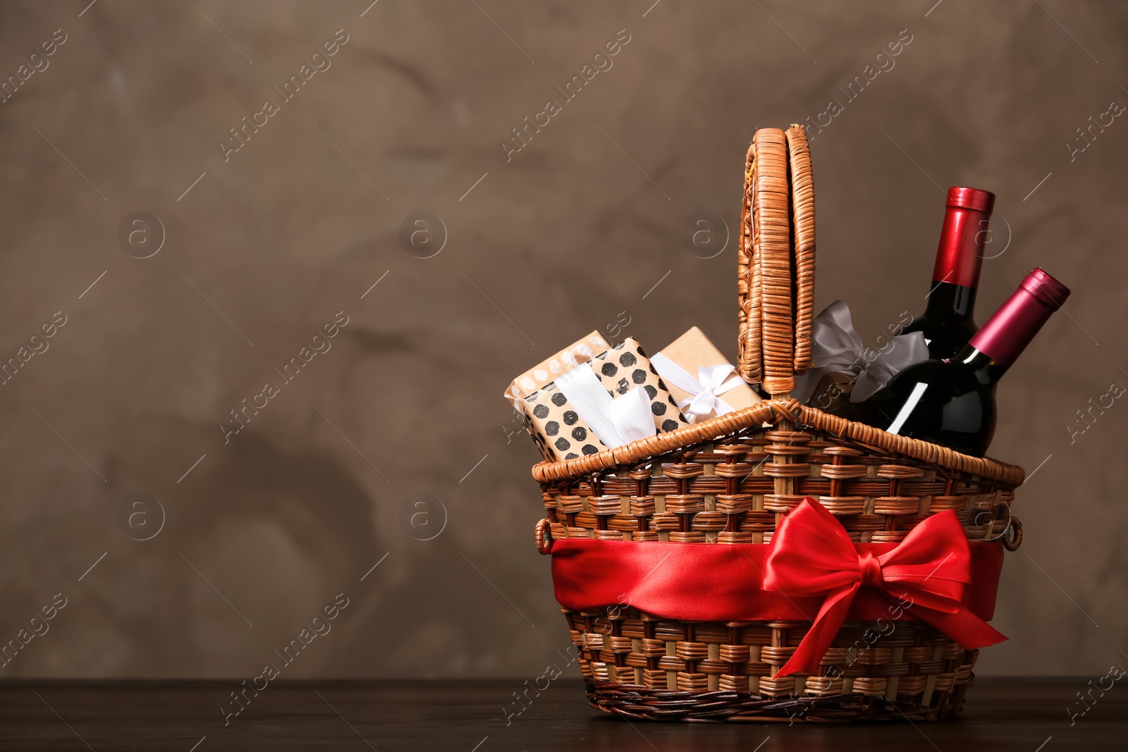 Photo of Gift basket with bottles of wine on dark background. Space for text