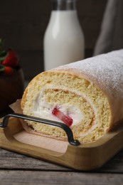 Photo of Delicious sponge cake roll with strawberries and cream on wooden table, closeup