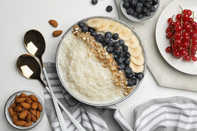 Photo of Delicious rice pudding with banana, blueberries and almond on light table, flat lay