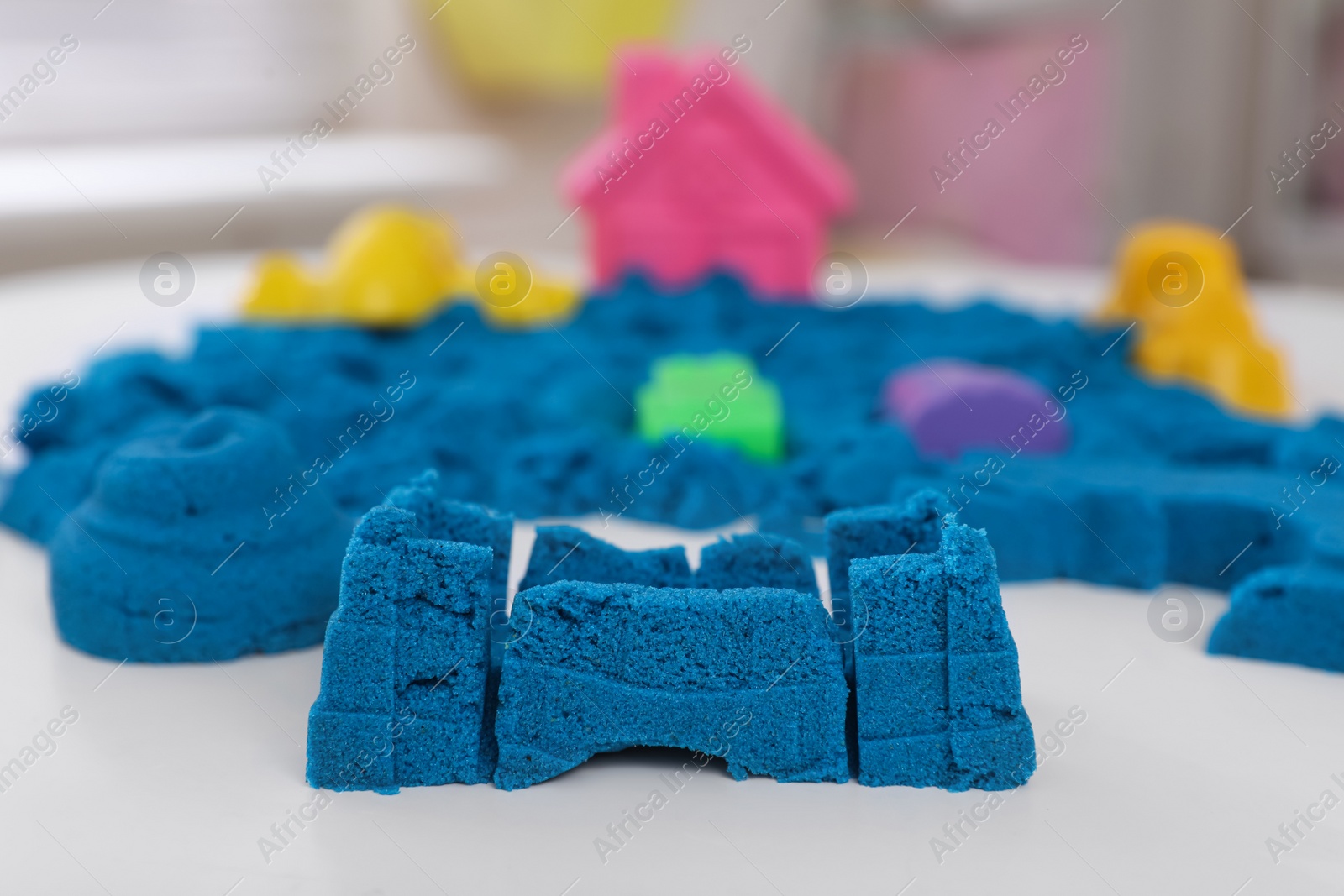 Photo of Bright kinetic sand on white table indoors