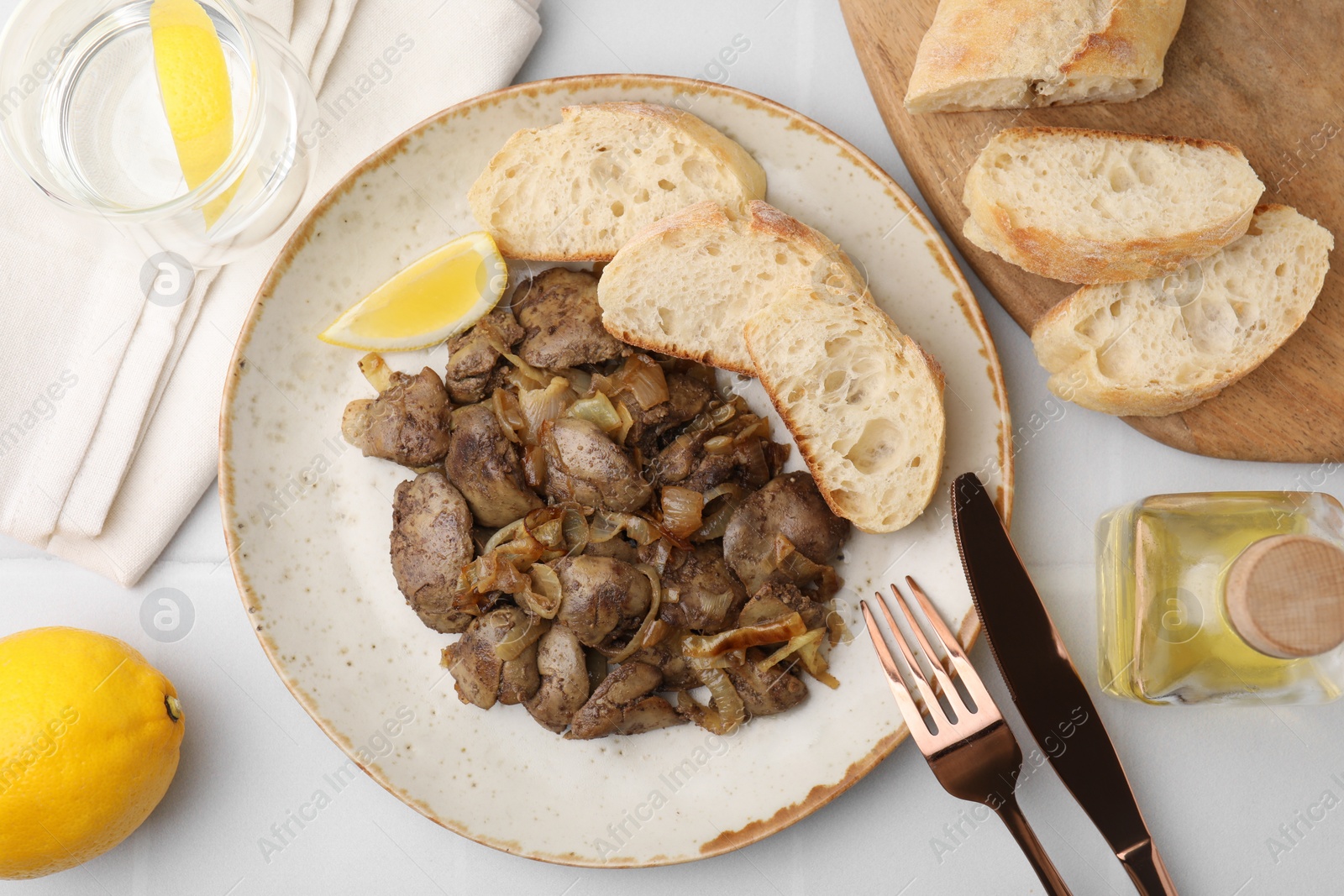 Photo of Tasty fried chicken liver with onion served on white tiled table, flat lay