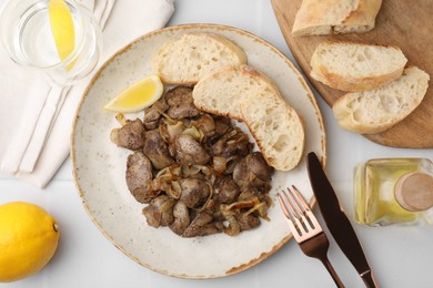 Tasty fried chicken liver with onion served on white tiled table, flat lay