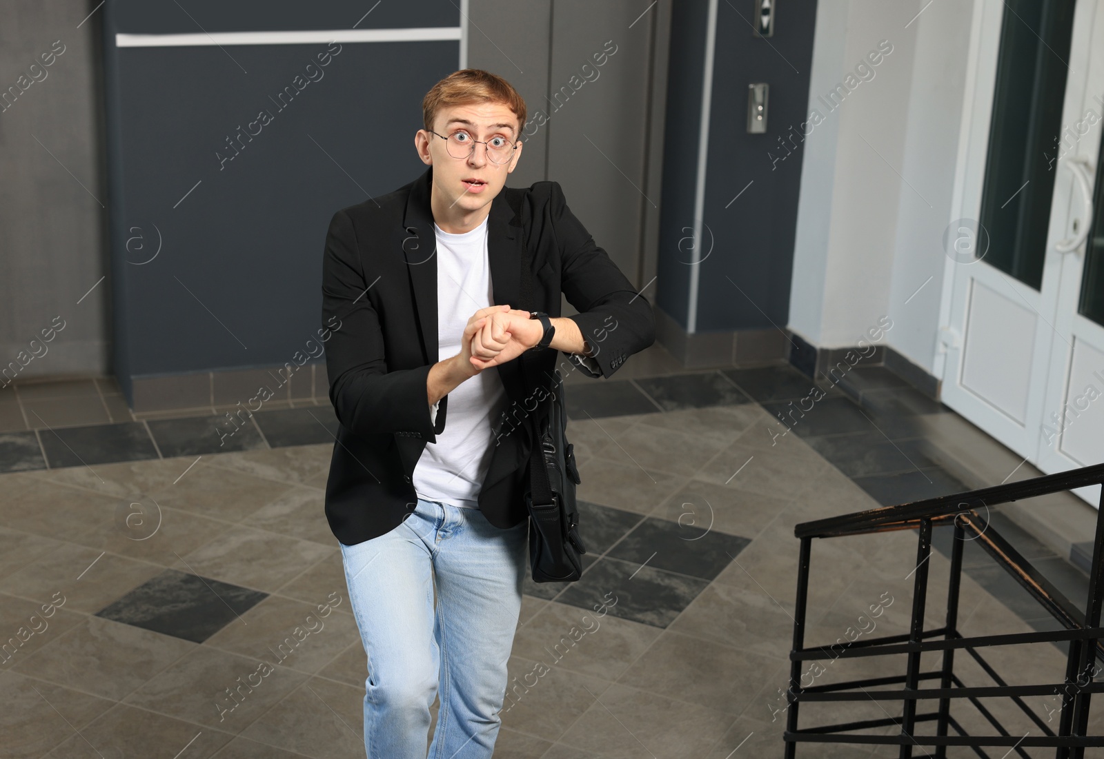 Photo of Emotional young man checking time in office. Being late