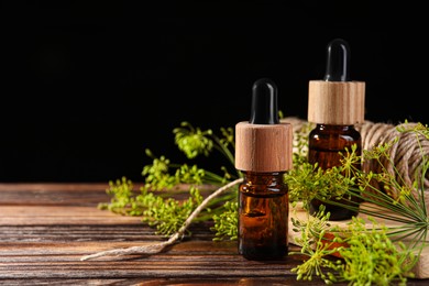 Photo of Bottle of essential oil, fresh dill and twine on wooden table, closeup. Space for text