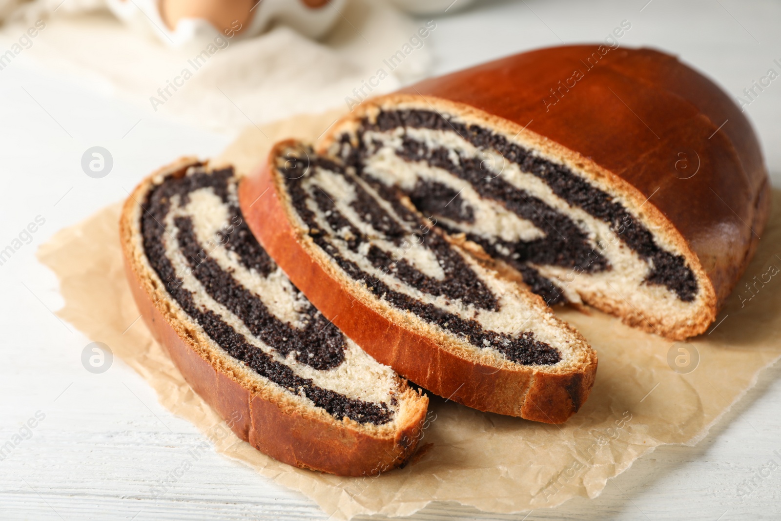 Photo of Cut tasty sweet bun with poppy seeds on wooden table