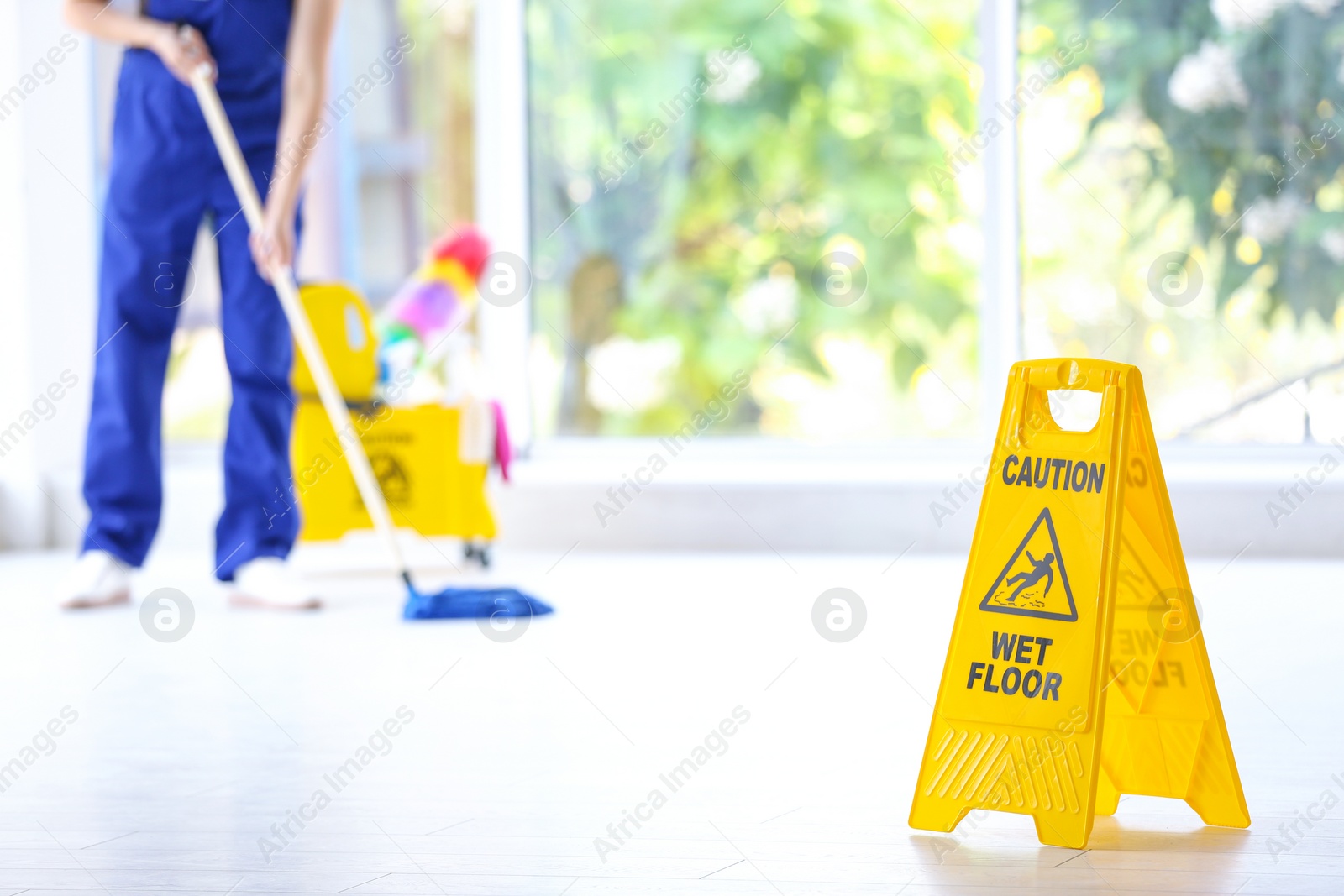 Photo of Safety sign with phrase Caution wet floor and cleaner indoors. Cleaning service