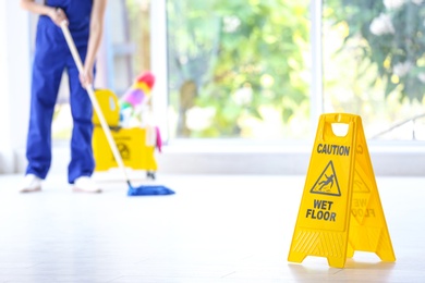 Photo of Safety sign with phrase Caution wet floor and cleaner indoors. Cleaning service