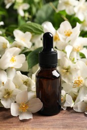 Photo of Jasmine essential oil and fresh flowers on wooden table