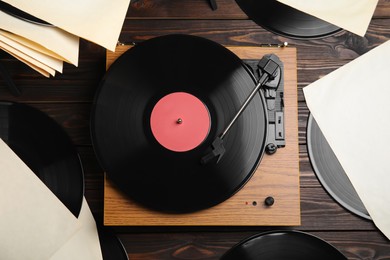 Photo of Modern player and vinyl records on wooden background, flat lay