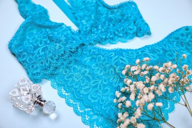 Photo of Elegant blue women's underwear, perfume and gypsophila flowers on light background, closeup
