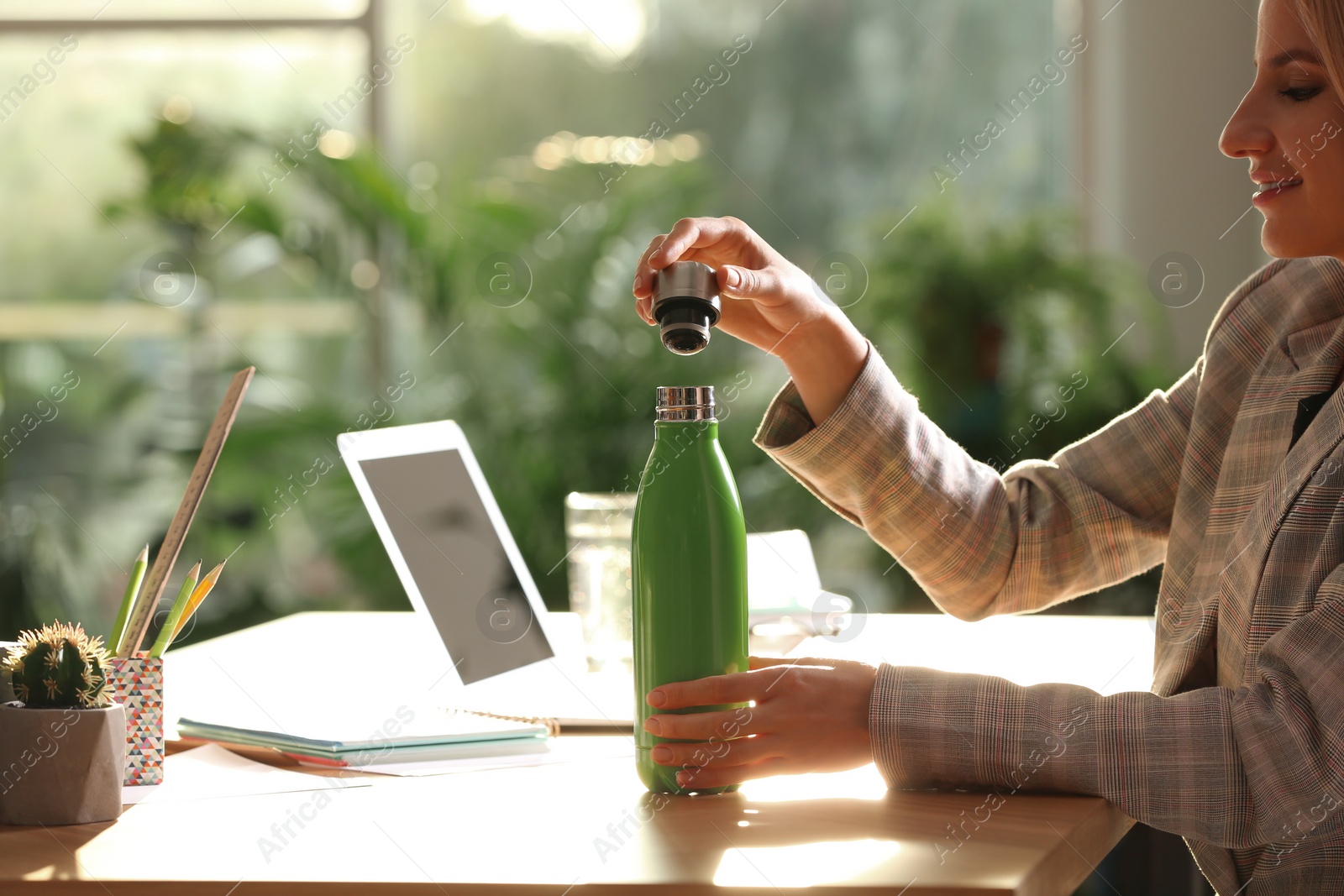 Photo of Woman with green thermos bottle at workplace