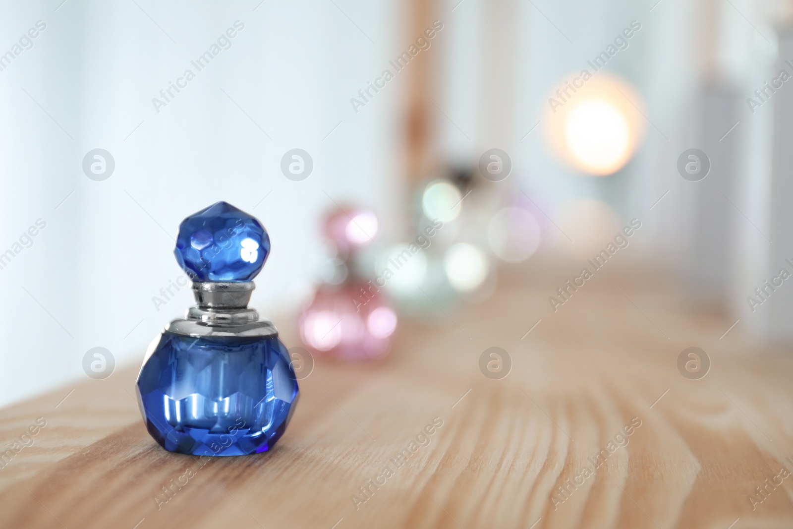 Photo of Perfume bottle on wooden shelf indoors. Space for text