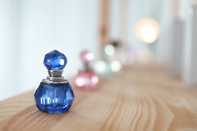 Photo of Perfume bottle on wooden shelf indoors. Space for text