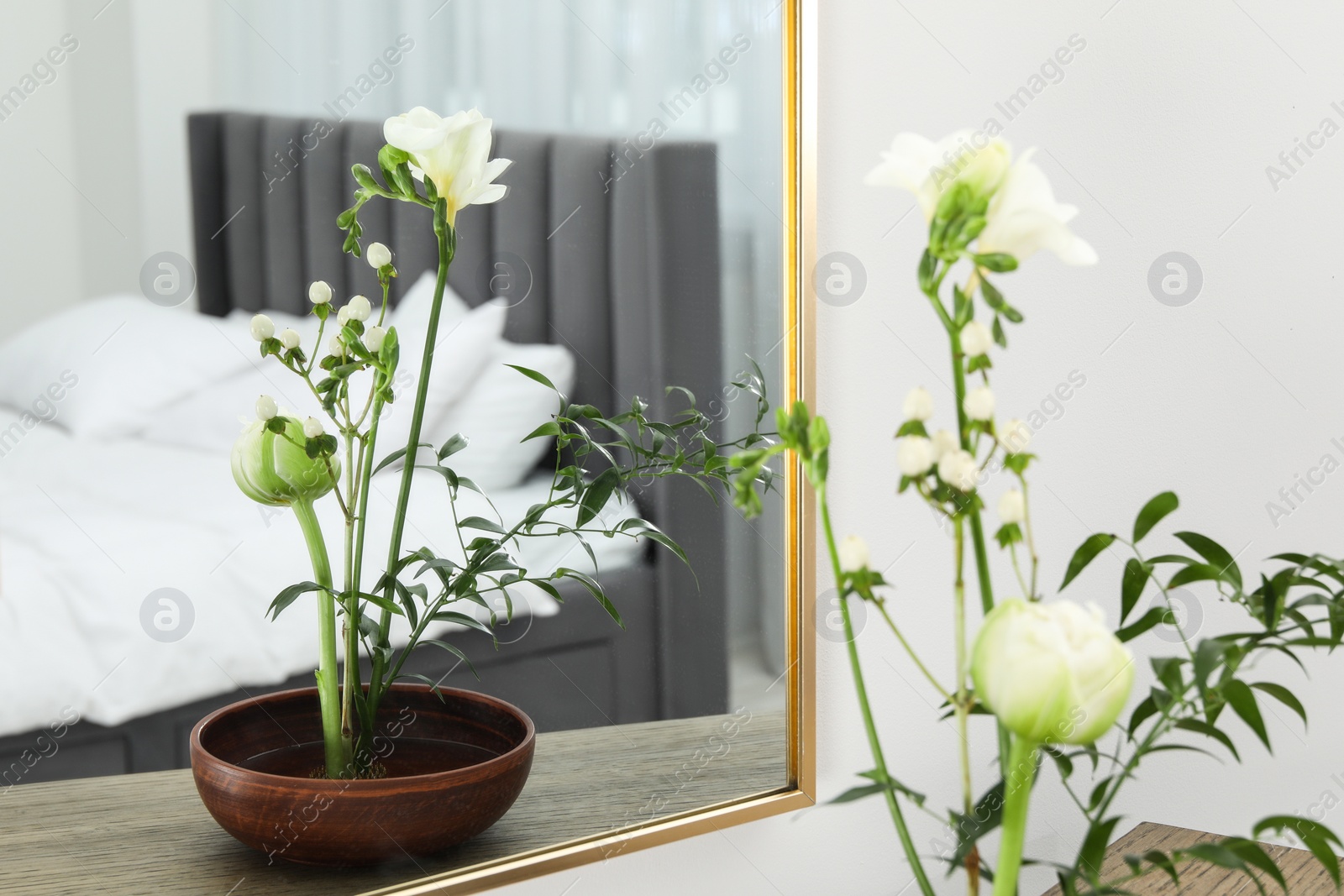 Photo of Stylish ikebana with beautiful flowers and green branch carrying cozy atmosphere at home