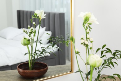 Photo of Stylish ikebana with beautiful flowers and green branch carrying cozy atmosphere at home