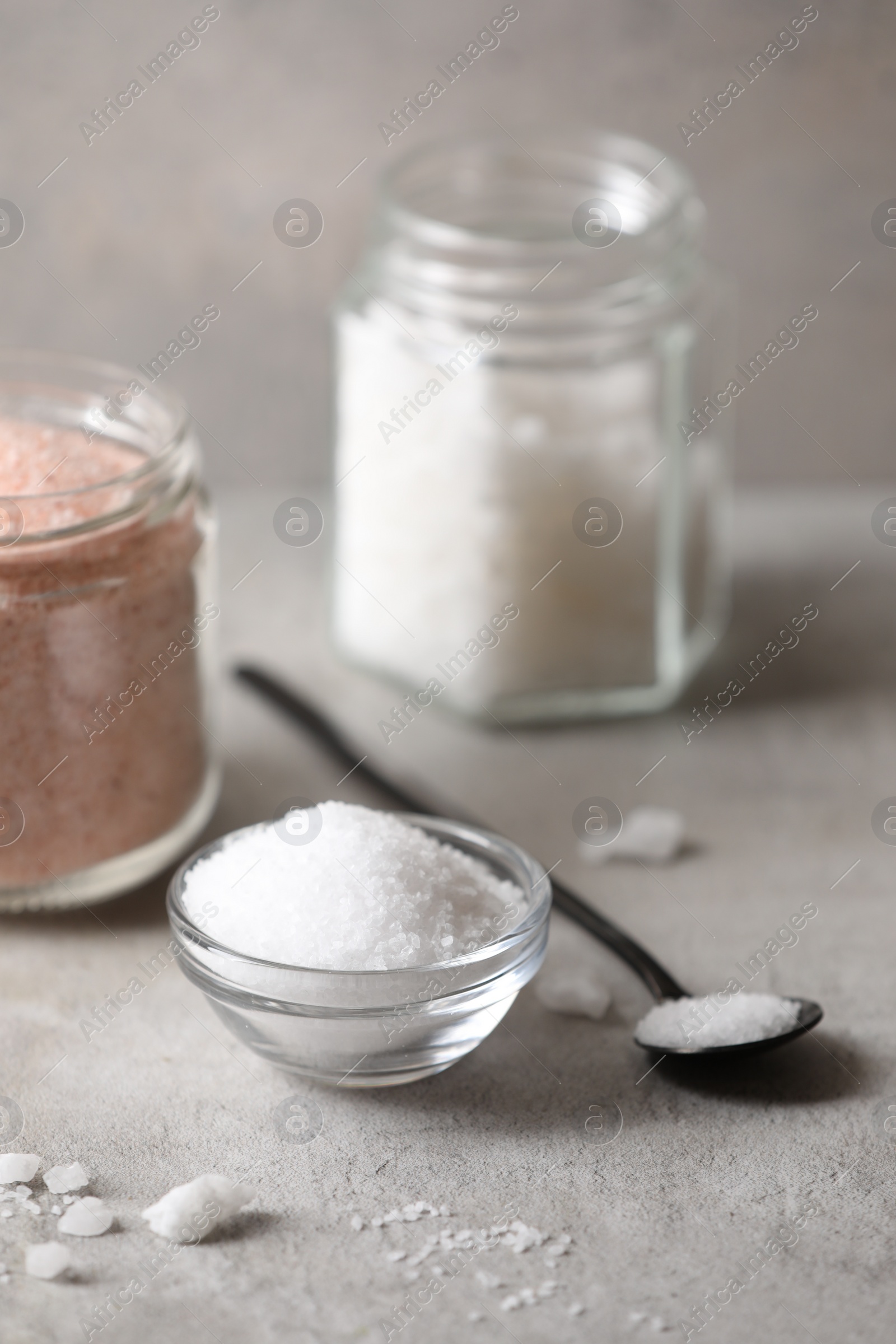 Photo of Different natural salt on grey table, closeup